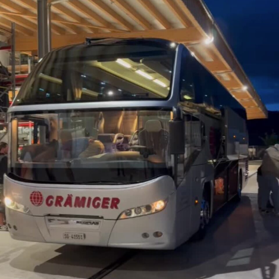 Reisebus von Grämiger nachts an überdachter Haltestelle