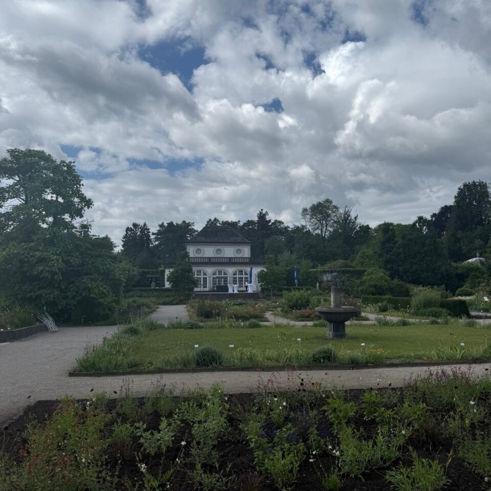 Pavillon im Garten unter dramatischem Wolkenhimmel