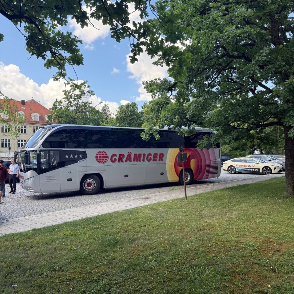 Grämiger Reisebus unter großen Bäumen am Straßenrand