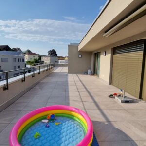 Großer Balkon mit buntem Planschbecken im Vordergrund.