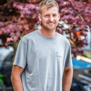Mann im grauen T-Shirt vor lila Baum
