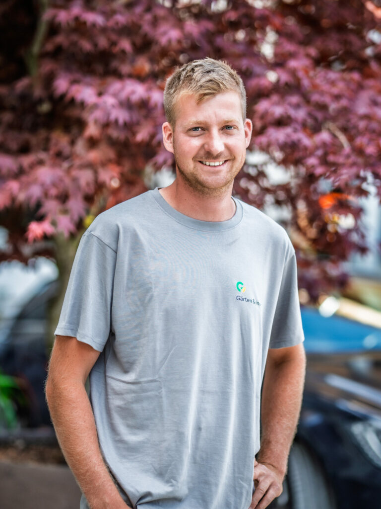Mann im grauen T-Shirt vor lila Baum