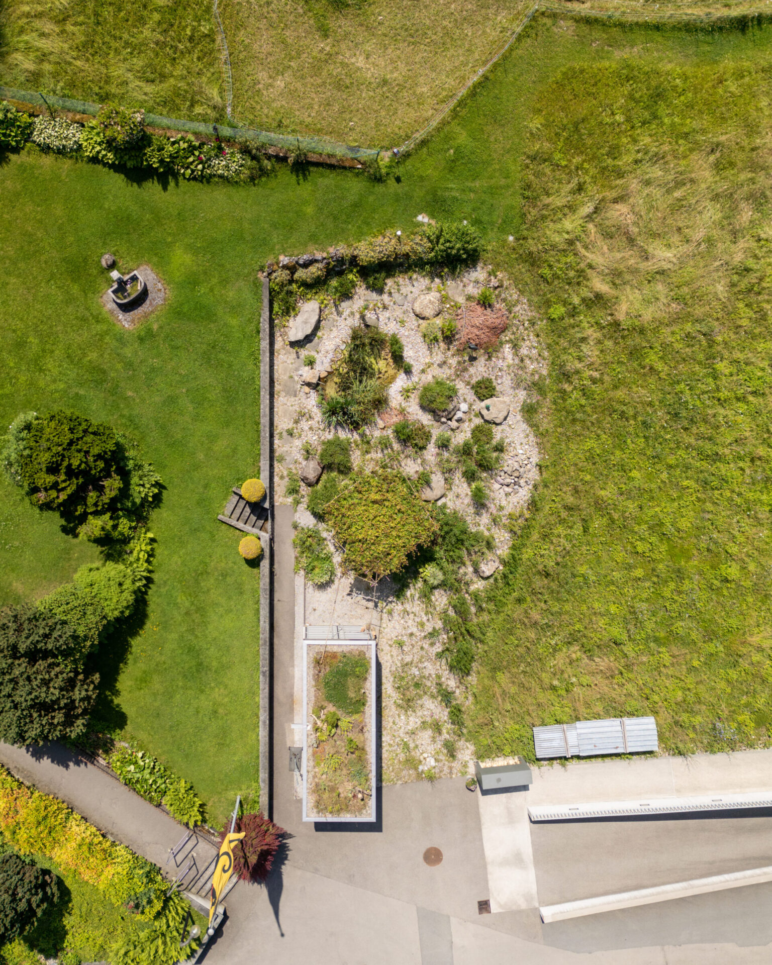 Drohnenansicht eines Gartens mit Rasen und Steingarten.