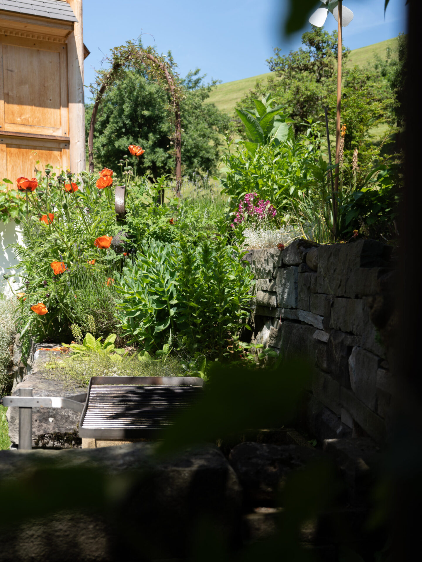 Grüner Garten mit Blumen und Grillplatz
