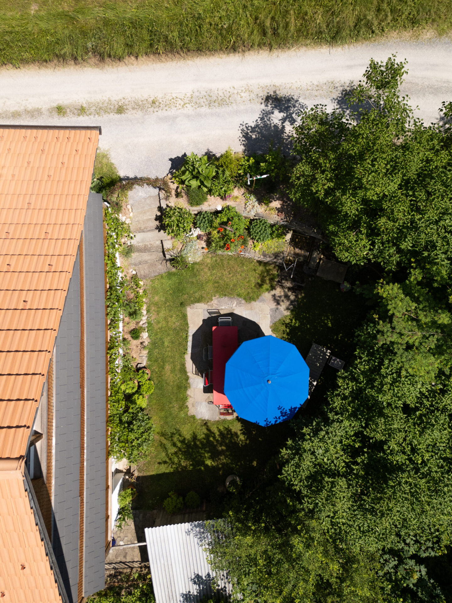 Drohnenaufnahme Garten mit Tisch und Sonnenschirm.