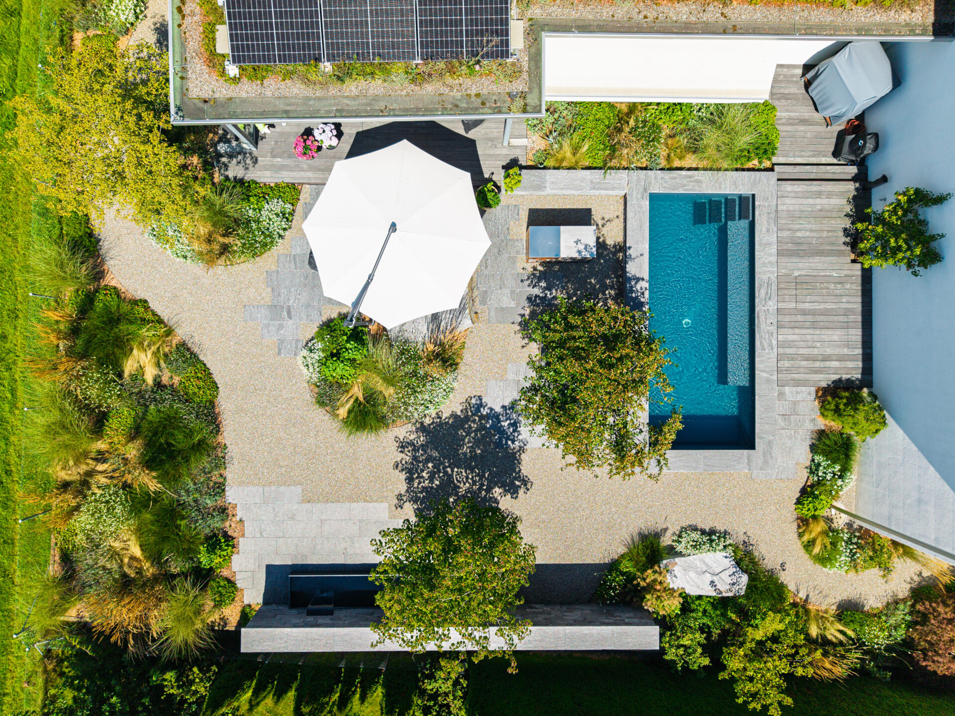 Luftansicht Garten mit Pool und Sonnenschirm.