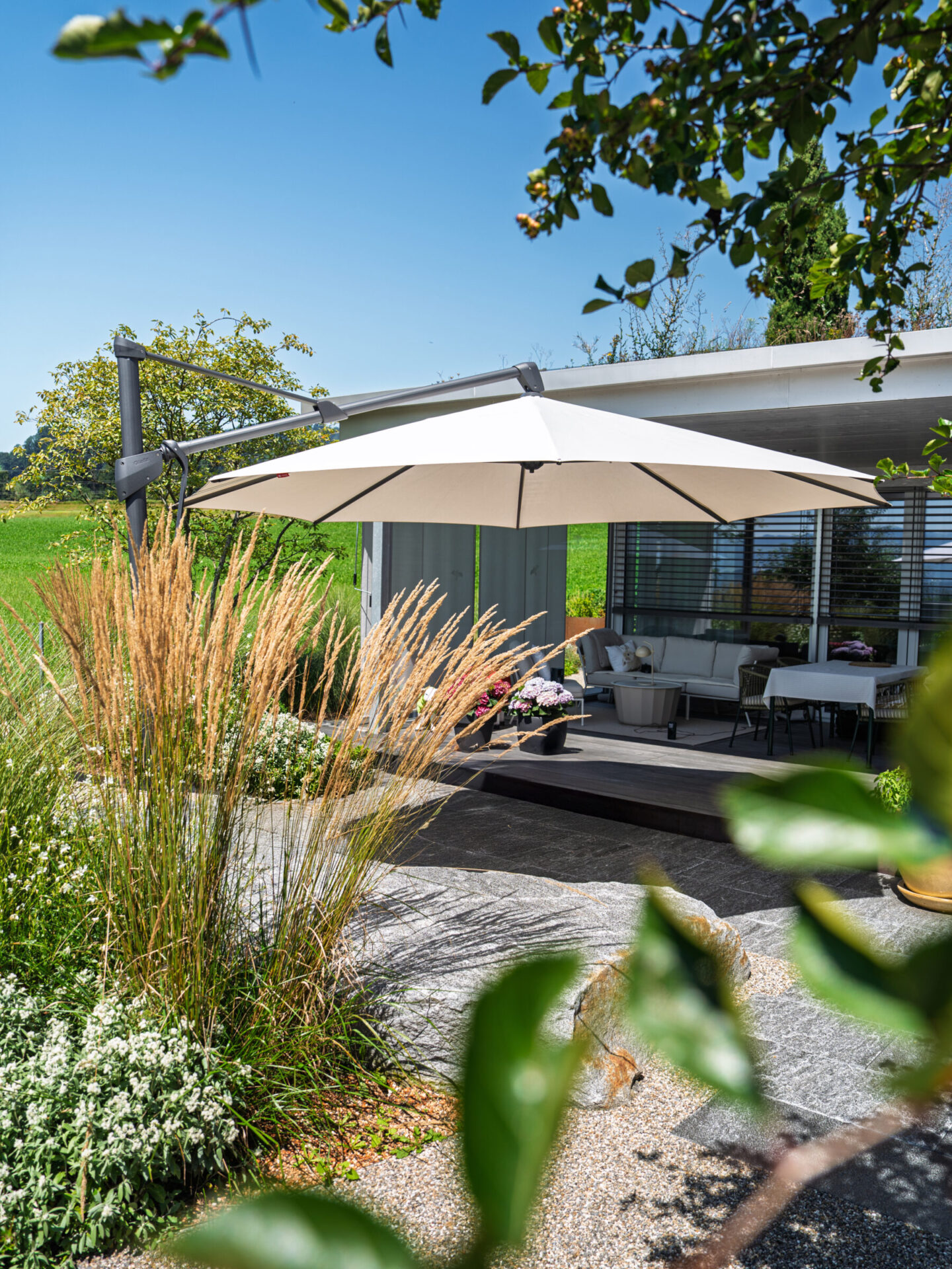 Terrasse mit Sonnenschirm und Garten im Sommer