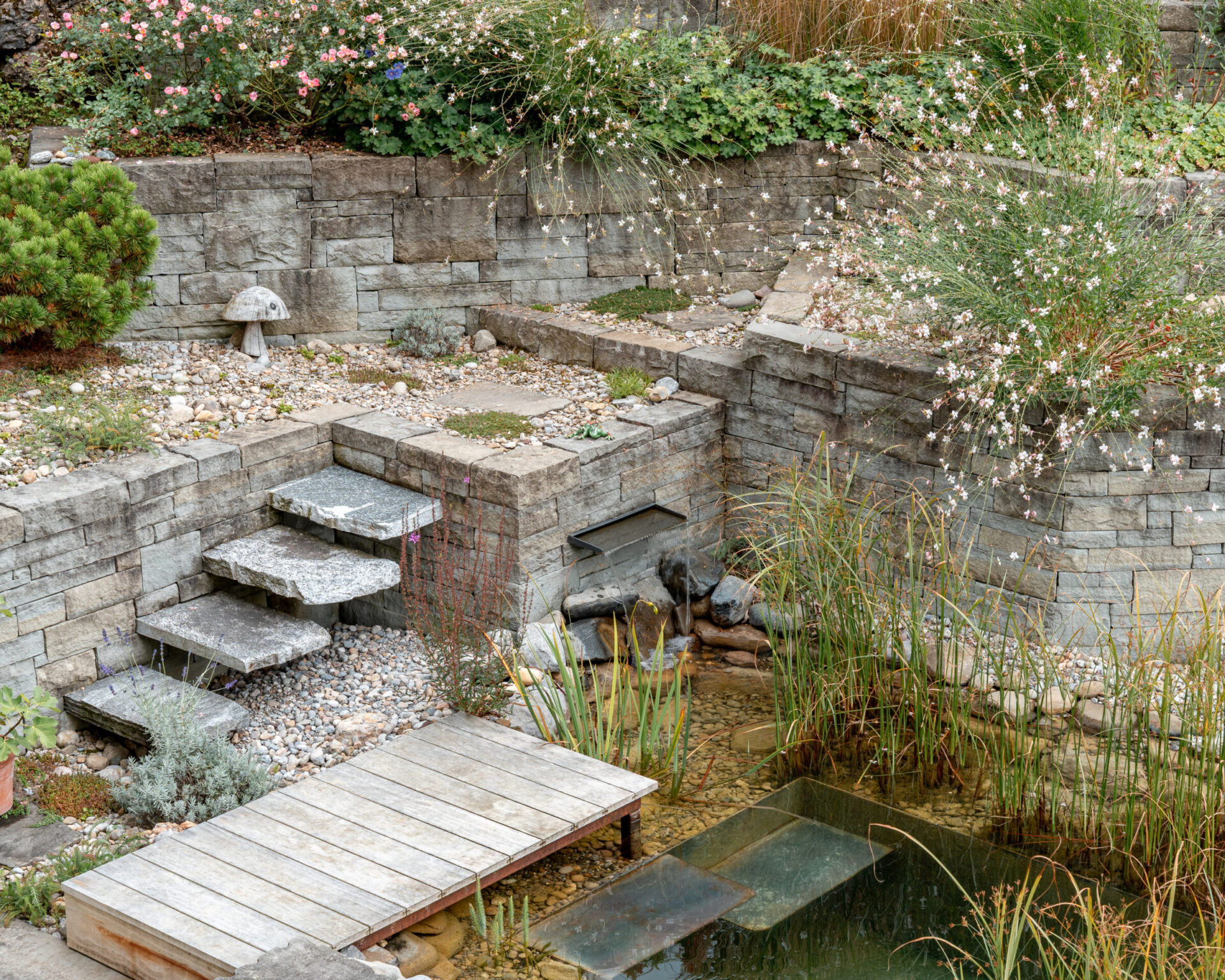 Steingarten mit Teich und grüner Vegetation.