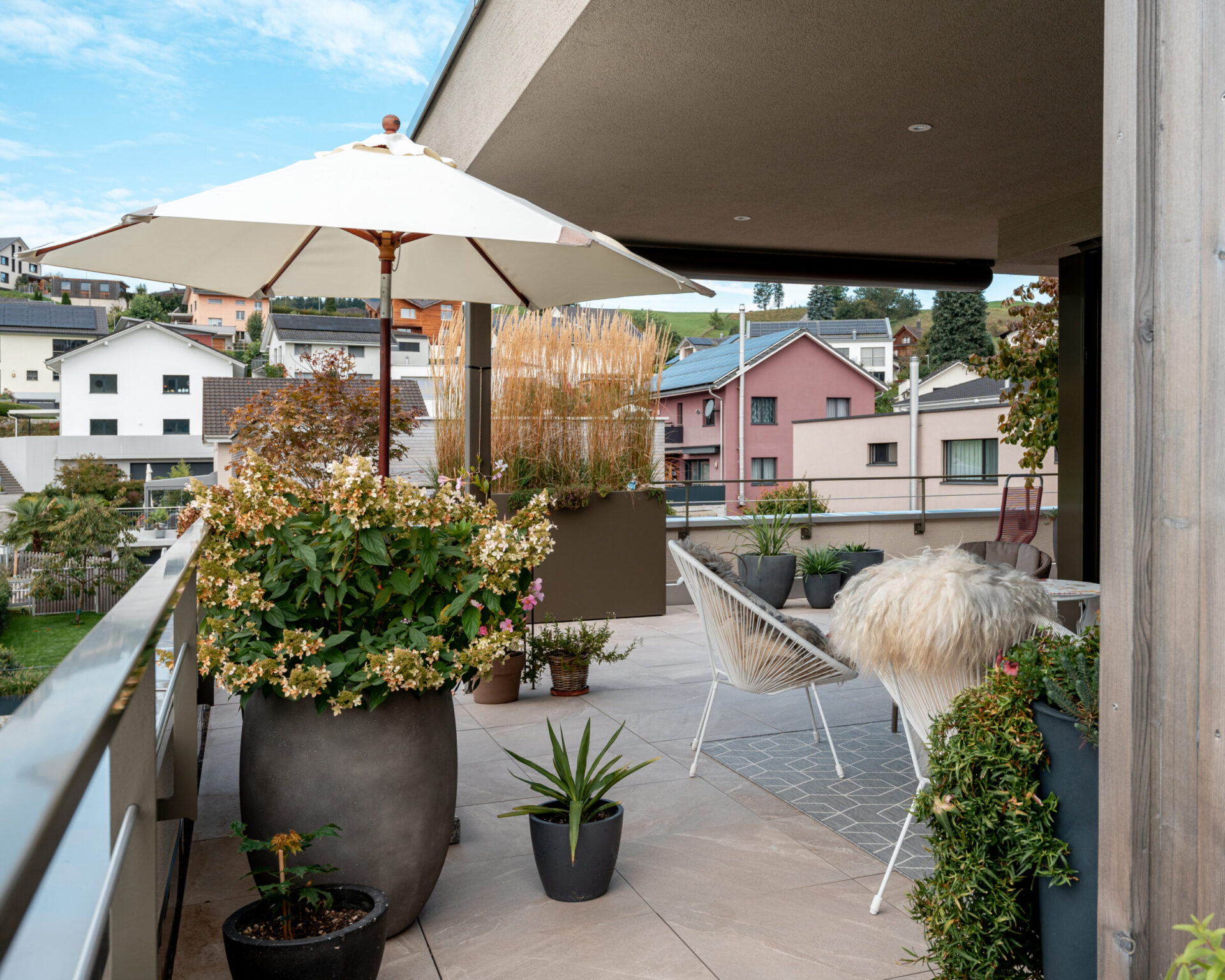 Moderne Terrasse mit Pflanzen und Sitzbereich.
