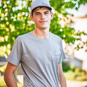 Mann im grauen T-Shirt vor grünem Hintergrund.