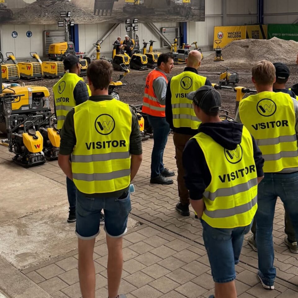 Besucher in Warnwesten bei Ausstellung von Wacker-Neuson-Baumaschinen