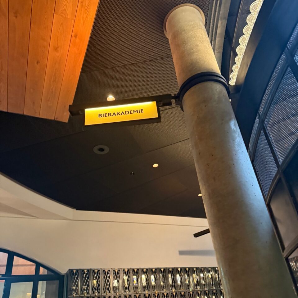 Leuchtschild „Bierakademie“ neben Säule im Innenraum