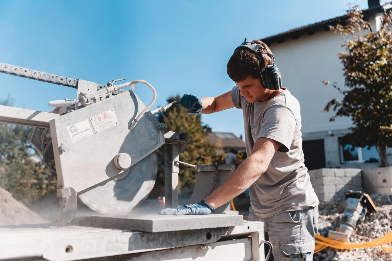 Arbeiter bedient grosse Kreissäge im Freien