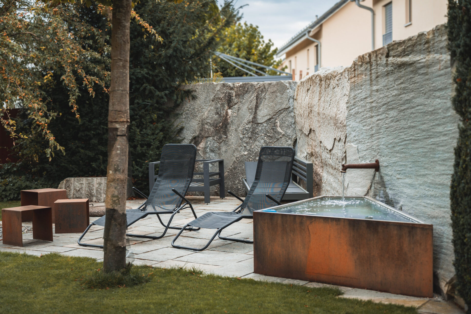 Gartenlounge mit Liegen und Wasserbrunnen