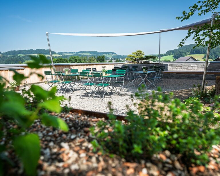 Sonnenterrasse mit grünen Stühlen und Ausblick.