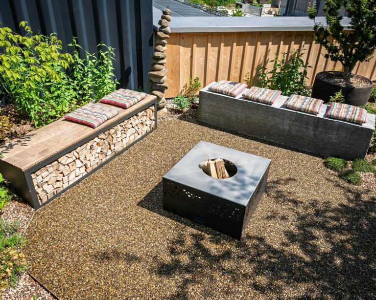 Moderner Garten mit Sitzbänken und Feuerstelle.