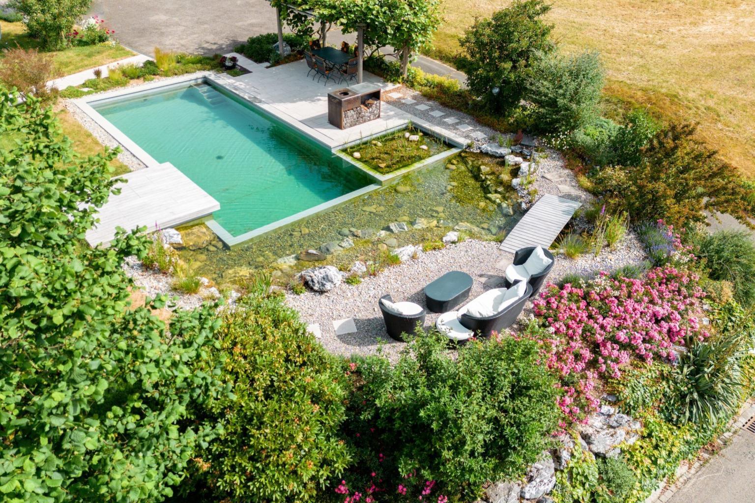 Garten mit modernem Pool und Blumenbeeten.