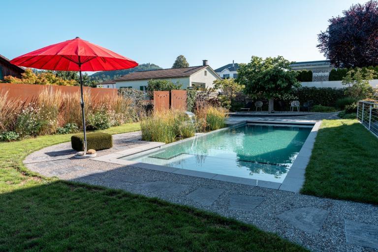 Garten mit Pool und rotem Sonnenschirm