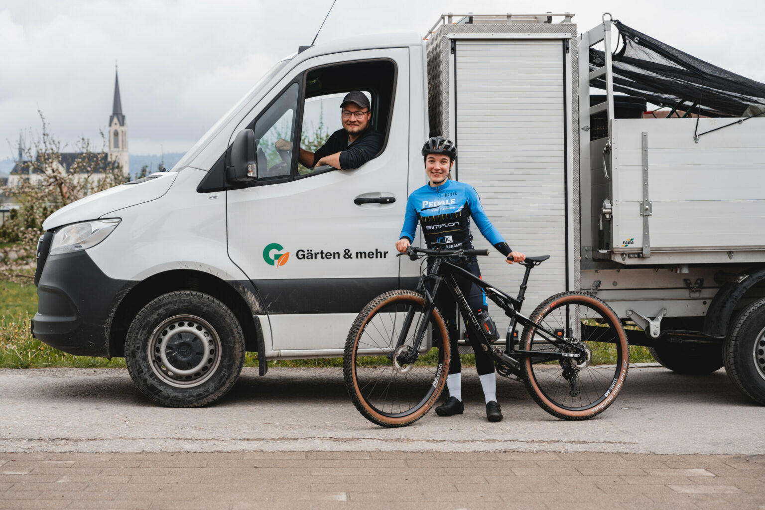 Lächelnder Radfahrer neben dem Lieferwagen in ländlicher Umgebung.