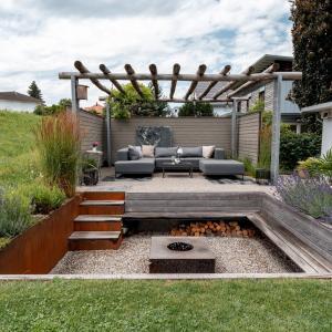 Moderne Gartenterrasse mit Sitzgruppe und Feuerstelle.