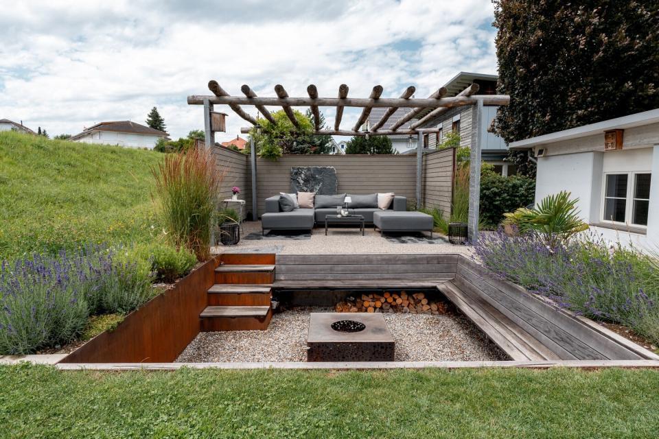 Moderne Gartenterrasse mit Sitzgruppe und Feuerstelle.