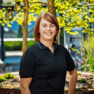 Frau im Freien unter Bäumen lächelnd