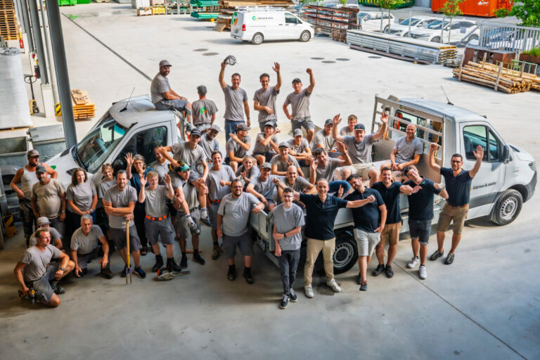 Gruppe von Menschen mit Autos auf Industriegelände.