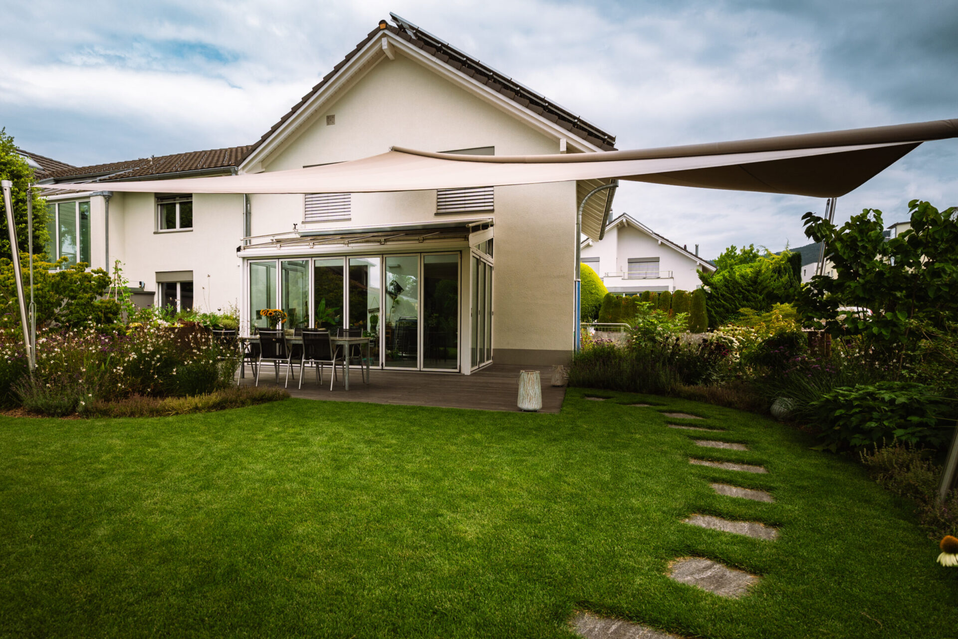 Moderner Garten mit Sonnensegel und Terrasse.