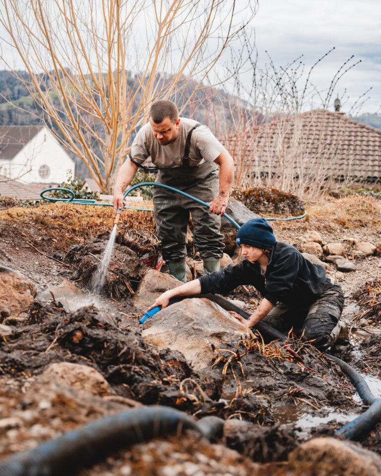 Menschen arbeiten im Garten mit Wasserschlauch