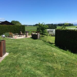 Grüner Garten mit Sitzbereich und Landschaftblick.