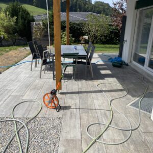 Terrasse mit Gartenschlauch und Tisch.