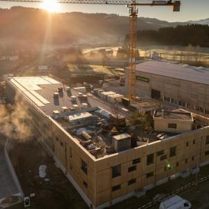 Gebäude im Bau bei Sonnenaufgang mit Kran im Hintergrund.