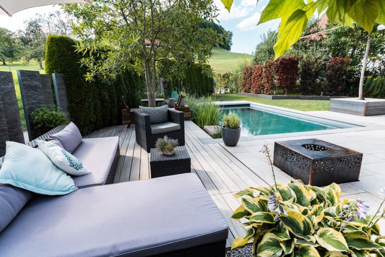Moderne Terrasse mit Pool und Gartenmöbeln.