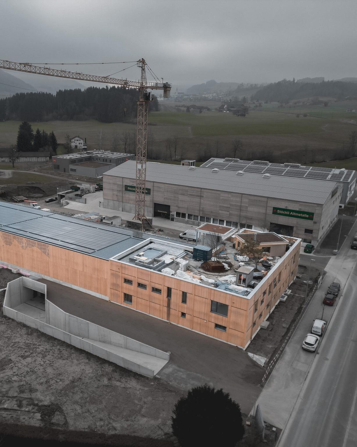 Industriegelände mit Kran und Gebäuden bei bewölktem Himmel.