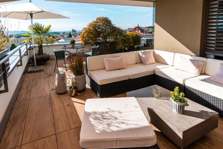 Moderne Terrasse mit Sofa und Pflanzen im Freien.